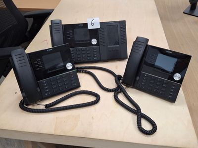 three black telephones sitting on top of a wooden desk next to each other