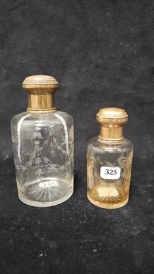 two small glass bottles with gold lids sitting on a black surface
