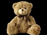un ours en peluche marron avec un nœud marron autour du cou