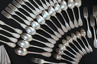 un grand nombre de cuillères et de fourchettes en argent disposées sur une table