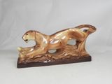 statue d'un lion en pleine course, posée sur un socle en bois, sur fond blanc
