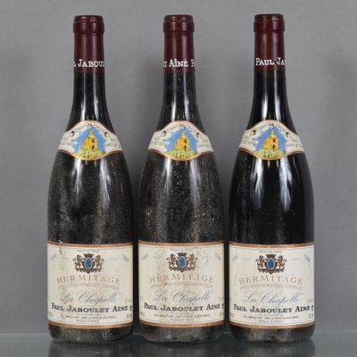 Trois bouteilles de vin sont alignées sur une table en verre