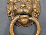 brass lion ' s head door knocket on a black door