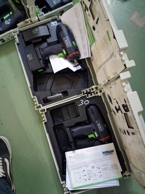 une boîte remplie d'outils posée par terre, près des pieds d'une personne