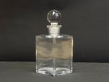une photo d'un flacon de parfum en verre transparent posé sur une table