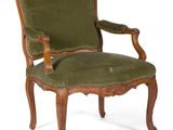 un fauteuil rembourré vert, avec une structure et des accoudoirs en bois