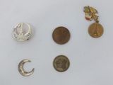 quatre types de broches différents et une pièce de monnaie posés sur une surface blanche