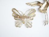 a butterfly brooch and a bird brooch on a white surface