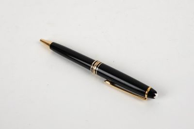 un stylo noir et or posé sur une surface blanche