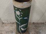 a green vase sitting on a cement floor next to a white wall