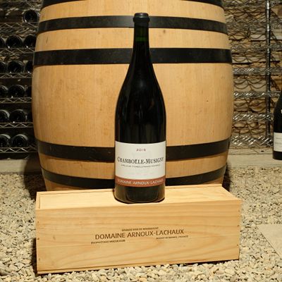 a bottle of wine sitting on top of a wooden barrel