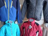 trois vestes exposées dans un magasin de vêtements, sur une table blanche