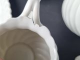 a person holding a white vase in their hand