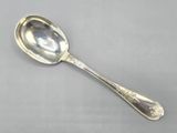une cuillère ancienne en argent posée sur une surface grise, avec un manche en argent