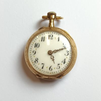 a close up of a gold pocket watch on a white surface
