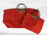 deux sacs rouges munis de poignées marron, posés sur une surface blanche
