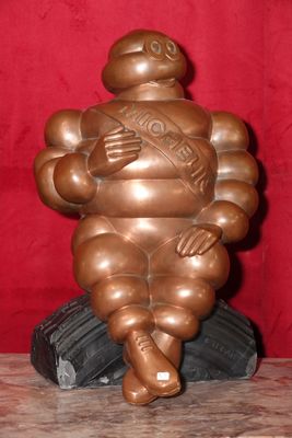 une statue en bronze représentant un homme corpulent assis sur une table