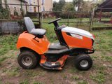 an orange riding lawn mower sitting in a yard next to a fence