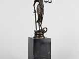 une statue en bronze représentant une femme tenant une balance, posée sur un socle en marbre