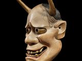 an image of a wooden mask with horns on a black background