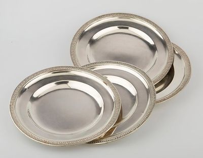 three silver plates with beaded rims on a white surface