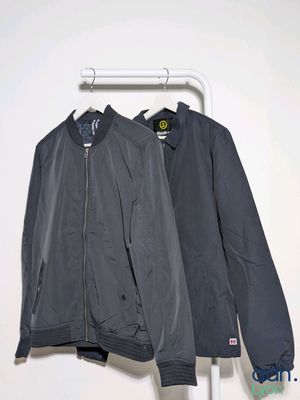 two jackets hanging on a clothes rack in a white room