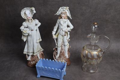 deux figurines placées à côté d'un vase en verre