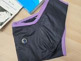 purple and black underwear on a table next to a book and a pair of shoes