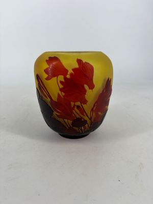yellow and red glass vase with red flowers on it on a white surface