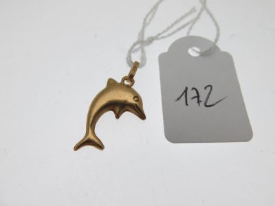 un petit pendentif en forme de dauphin en or, suspendu à une étiquette