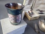 a silver cup sitting on top of a box next to a fork and spoon