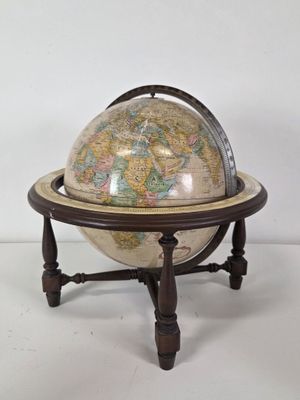 un vieux globe terrestre posé sur un socle, avec un fond blanc