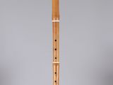 a wooden flute on a clear stand against a gray background
