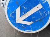 a blue and white sign with an arrow on it