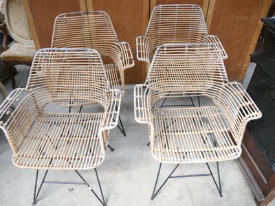 trois chaises en osier blanc placées les unes à côté des autres dans une pièce