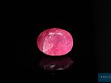 un gros plan d'une pierre rose sur une surface noire