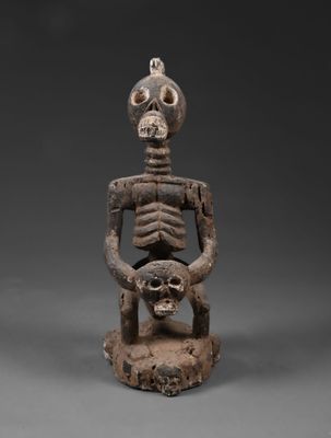 une statue représentant un squelette assis sur une chaise dont le dossier est orné d'un crâne