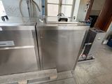 two stainless steel ovens sitting on a pallet in a room