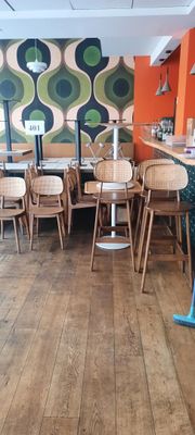 de nombreuses chaises et tables dans un restaurant, avec un mur coloré en arrière-plan