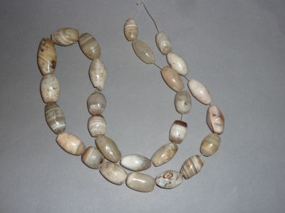 un collier composé de perles blanches et marron sur un fond gris