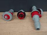 two red and gray electrical plugs sitting on a wooden surface