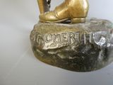 une statue en bronze représentant un homme tenant une raquette de tennis