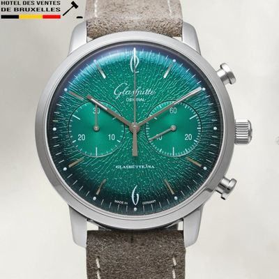 a close up of a watch with a green face