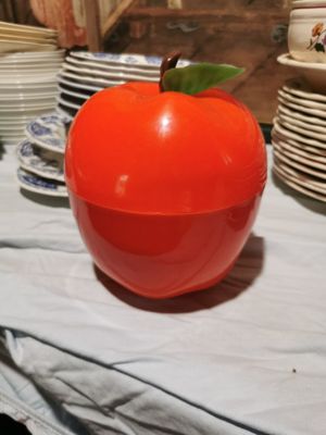 a large red apple sitting on a table with many plates