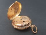 a gold pocket watch sitting on a black surface
