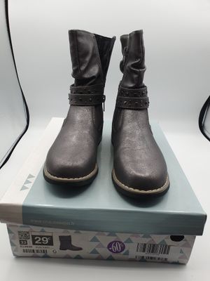 une paire de bottes noires pour femme posée sur une boîte, sur une surface blanche