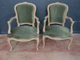 une paire de fauteuils en velours vert dans une pièce, avec un mur en arrière-plan