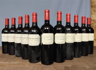 six bottles of red wine are lined up on a wooden table