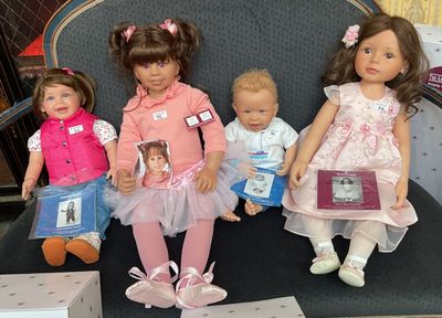 five dolls that are sitting on a chair together