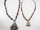 two necklaces with beads and a silver pendant on a white background